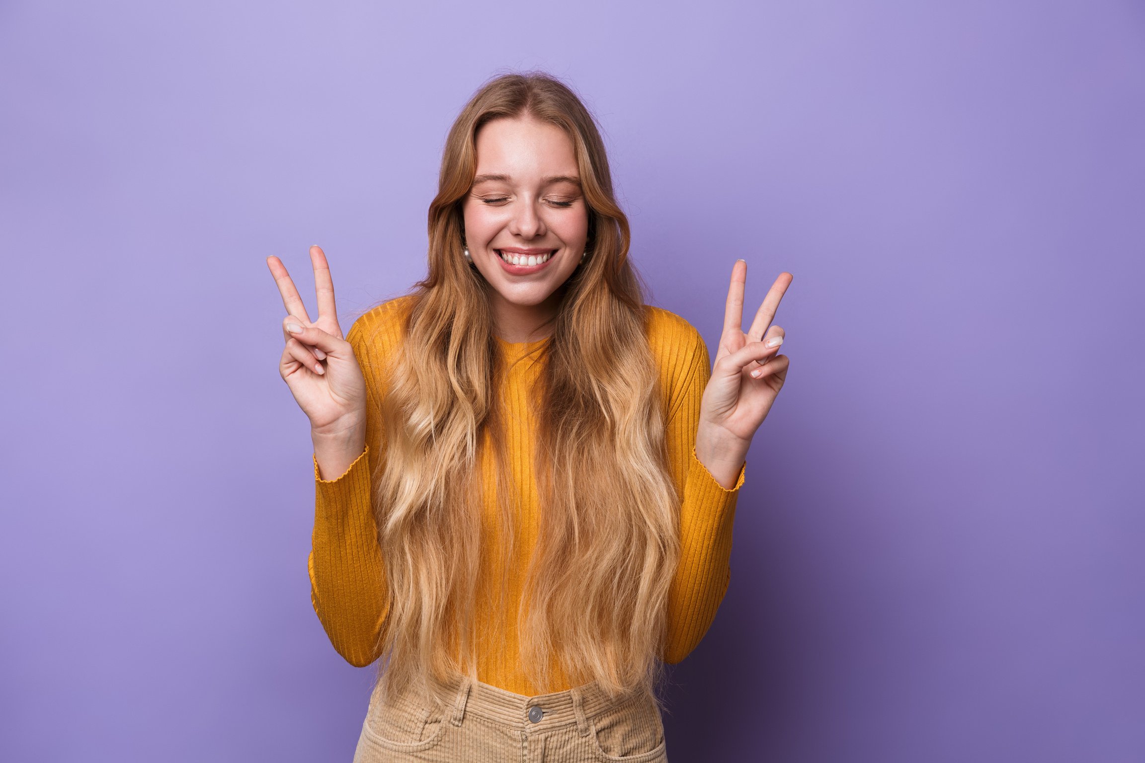 Photo of Cheerful Young Woman Laughing and Gesturing Peace Sign